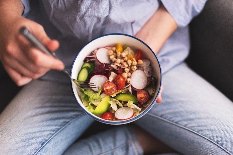 Persona comiendo vegetales ricos en ácido fólico. Alimentos y propiedades del ácido folico