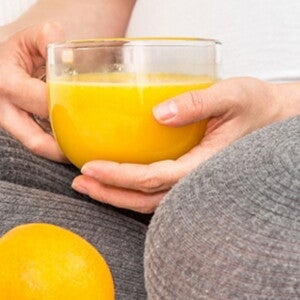 4 vitaminas importantes para antes de quedar embarazada Mujer con jugo de naranja con vitaminas para embarazarse