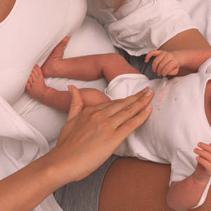 Baby lying on her back, having her belly caressed by a mother's hand. Baby lying on her back, having her belly caressed by a mother's hand.