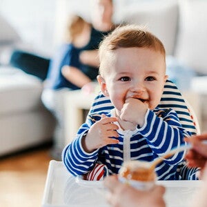 Bebé en su silla comiendo alimentos sólidos