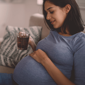 Pregnant woman on a couch, drinking tea and smiling. Pregnant woman on a couch, drinking tea and smiling.