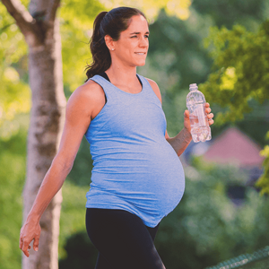 Pregnant woman exercising outdoors, holding a water bottle Pregnant woman exercising outdoors, holding a water bottle