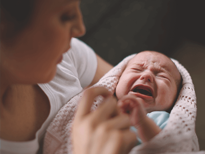 Woman holding a crying baby, trying to soothe him. Woman holding a crying baby, trying to soothe him.