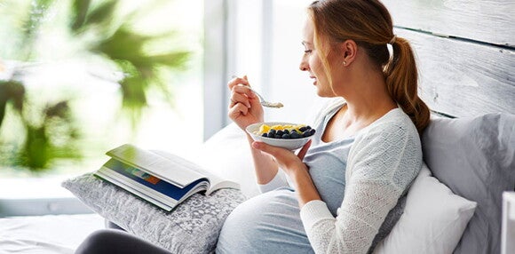 Mujer en embarazo comiendo un plato de frutas Mujer en embarazo comiendo un plato de frutas